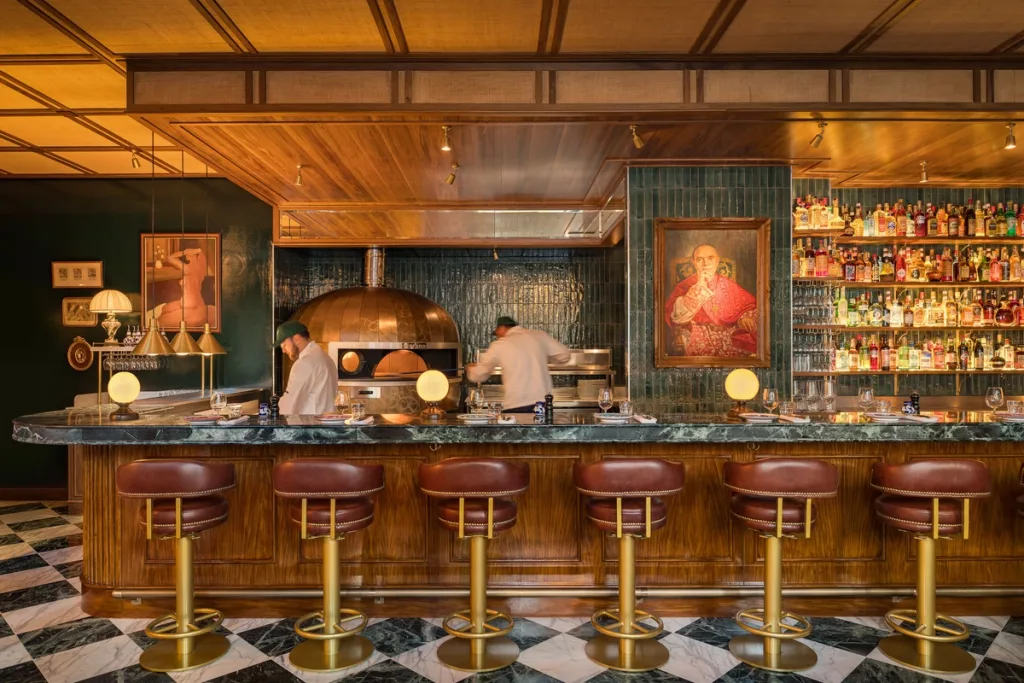 Restaurant staff behind a green-topped bar with brown stools at Big Mamma, UK