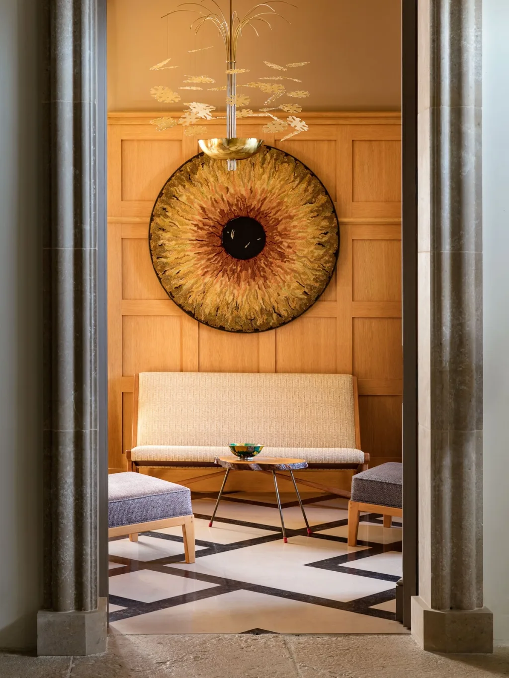 Circular artwork above a pale bench in the panelled sitting room at Fabrègues, Pierre Yovanovitch