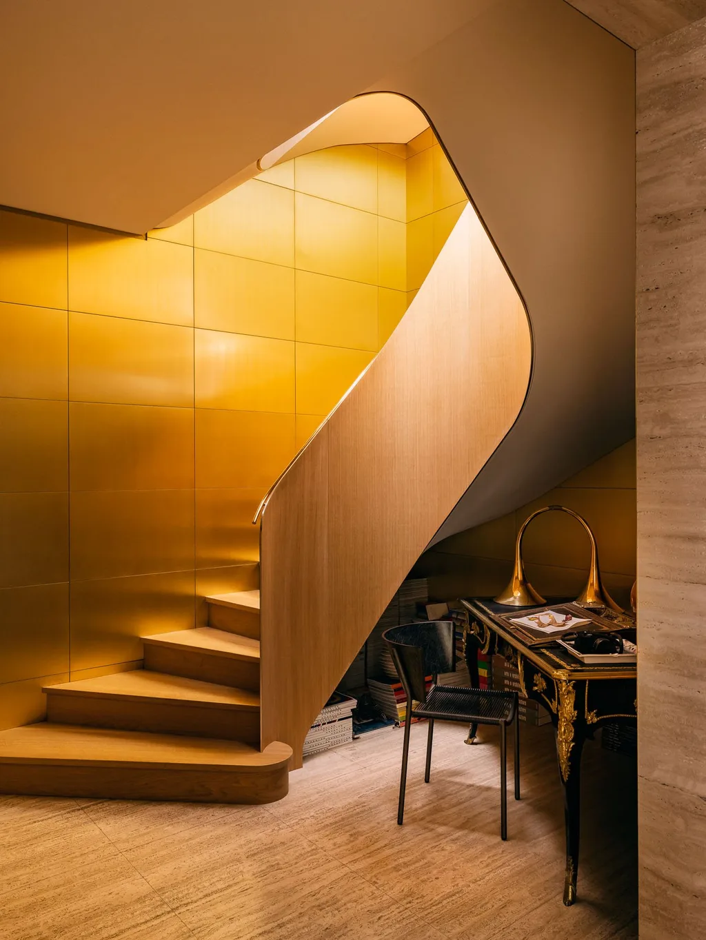 Curving wooden staircase against golden walls in Laurent Buttazzoni's Paris interior