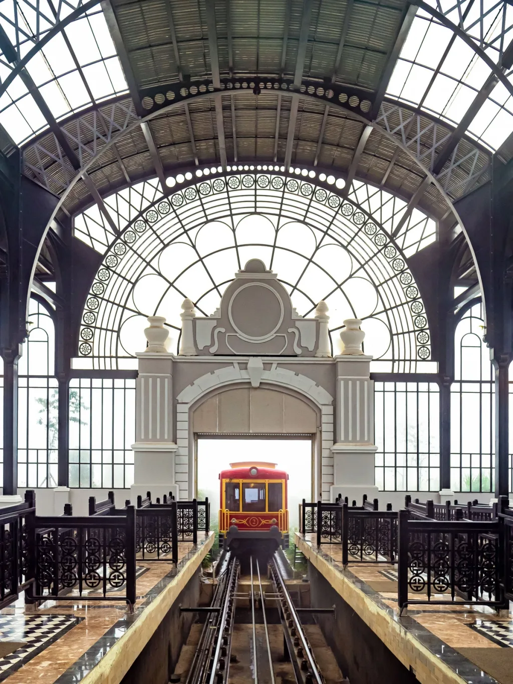 Red vintage funicular arrives under an ornate arched glass roof, Hotel de la Coupole MGallery, Sapa, Vietnam