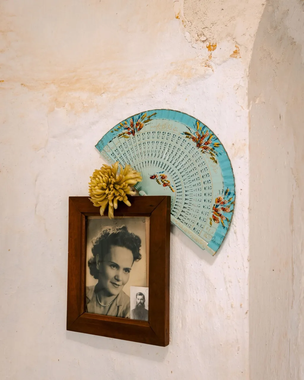 Framed black-and-white portrait beneath a turquoise fan on a textured wall in Almeria