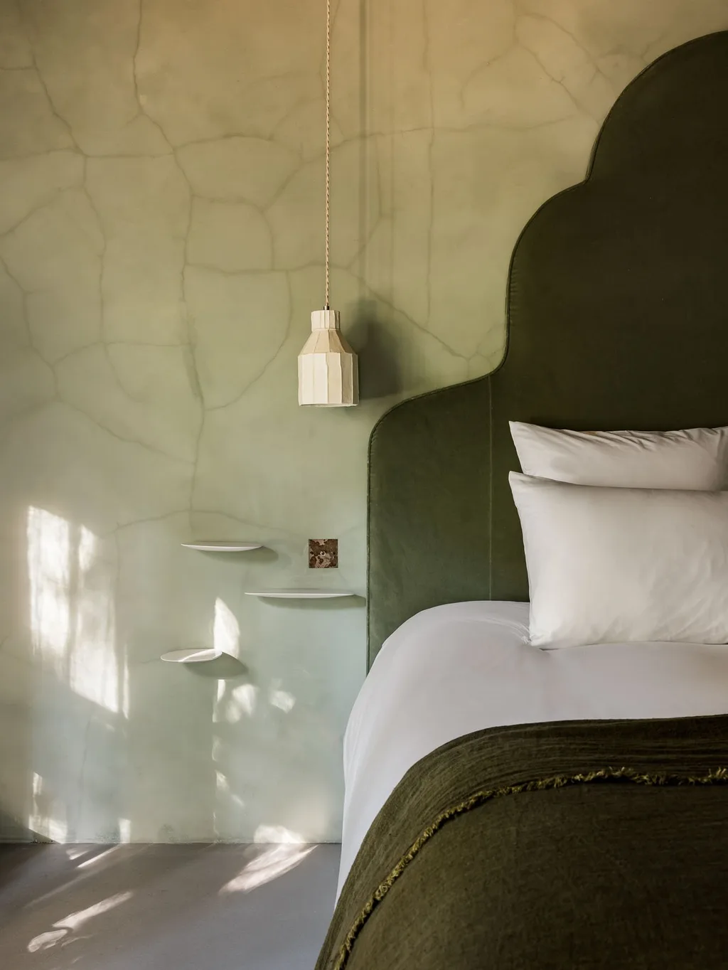 Green velvet headboard and olive plaster wall in a bedroom, Manufacture Royale de Lectoure hotel