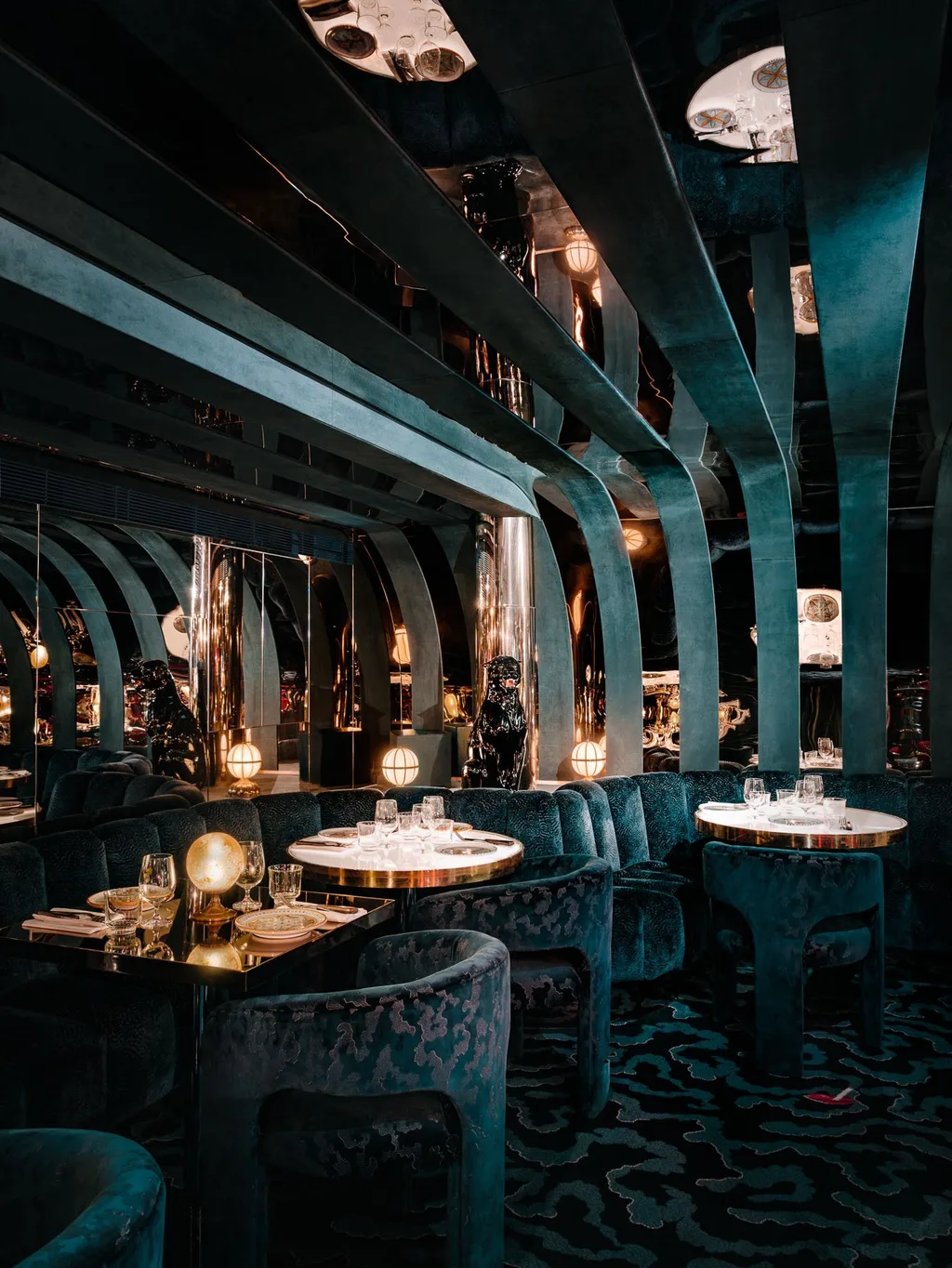 Dark teal dining room with curved ceiling ribs and globe lamps at Big Mamma, UK
