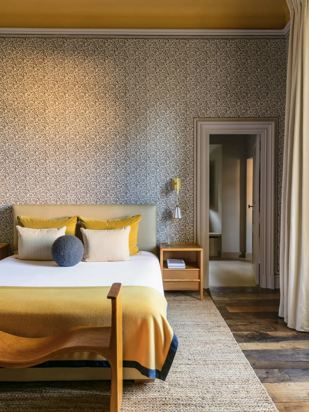 Yellow bedspread against patterned bedroom walls at Fabrègues, Pierre Yovanovitch