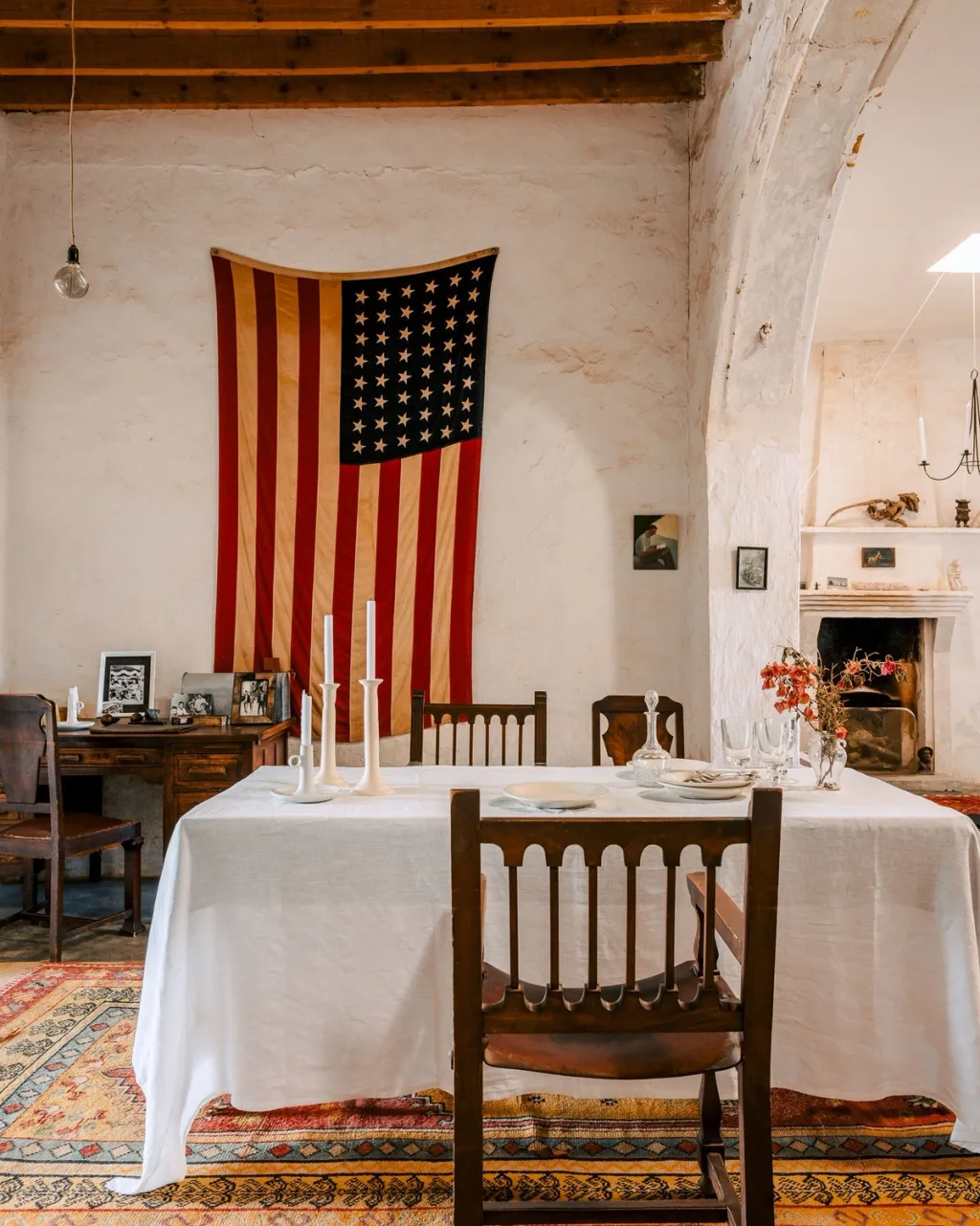 White-clothed dining table beneath an American flag and exposed beams in an Almeria home