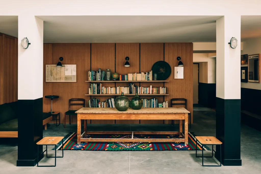 Farmhouse table and bookshelves on a colorful kilim rug, Le Barn hotel