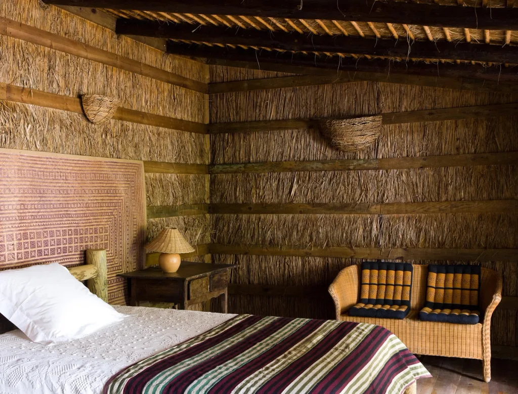 Rustic bedroom with reed-lined walls and striped textiles, Jacques Grange, Comporta