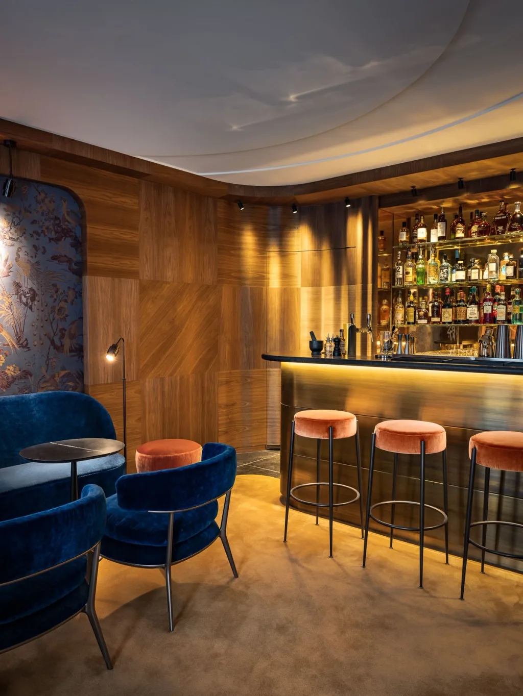 Curved brass bar with backlit bottle shelves at Hotel Pavillon St Germain, Paris