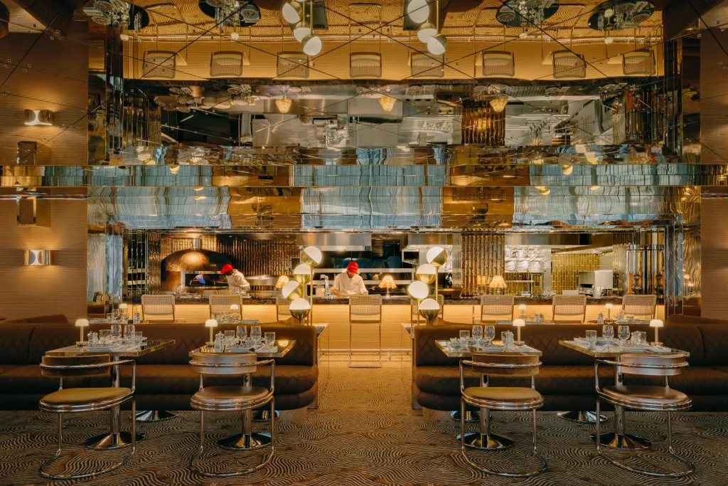Mirrored dining room facing an open kitchen with gold-toned fittings at Big Mamma, UK