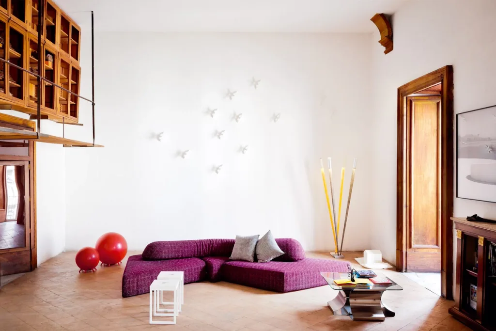 Low purple sectional sofa beneath small white wall sculptures in the Antonio G. Martiniello project, Naples