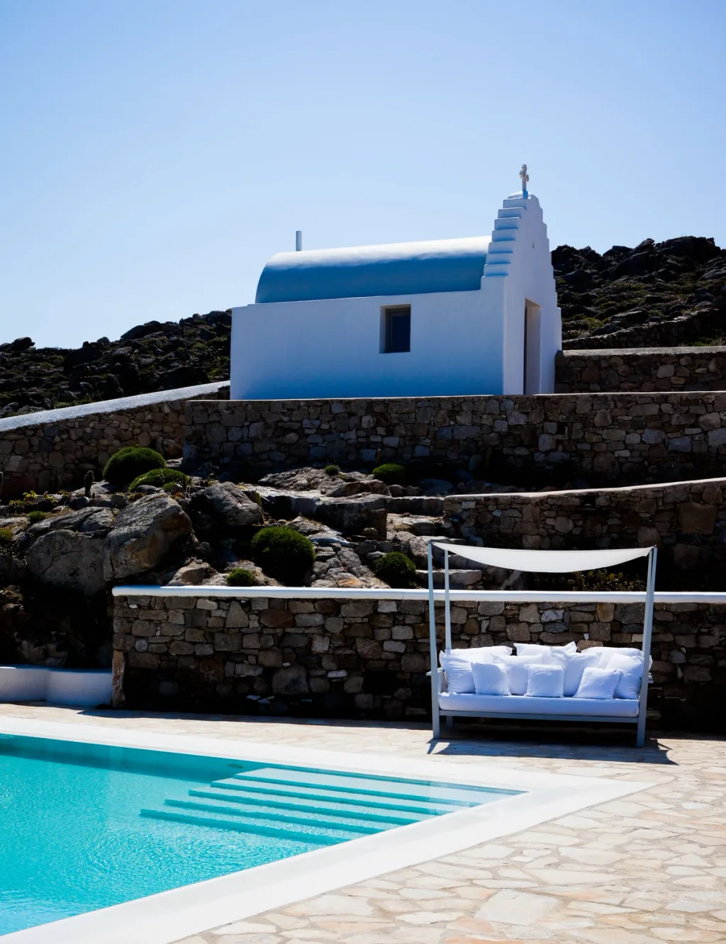 Stone wall with mounted antlers and a striped pergola shadow over breakfast, a hotel in Mykonos