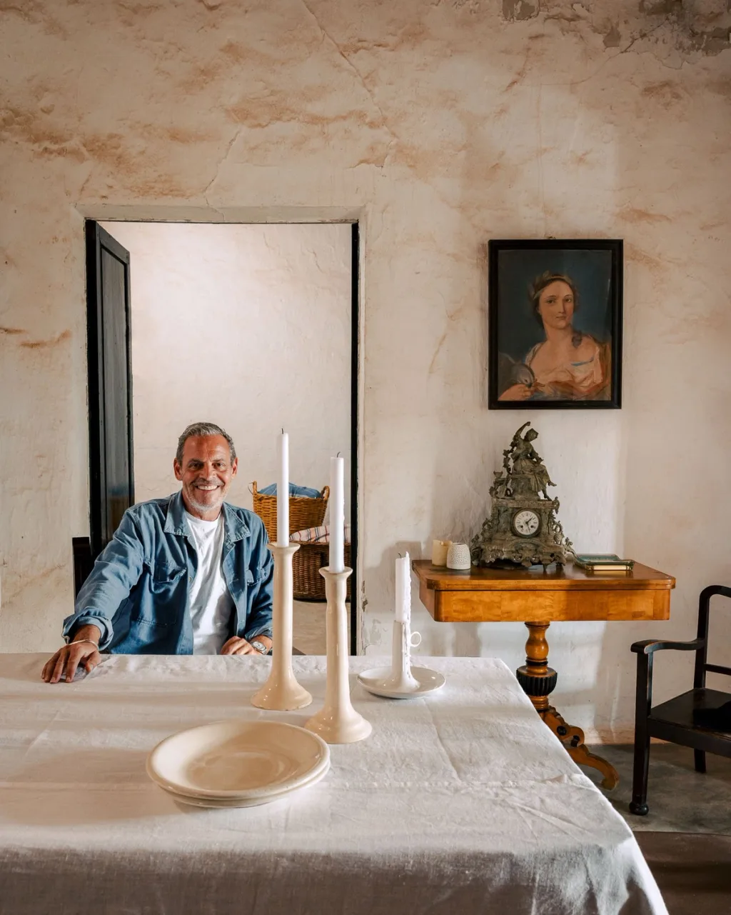 Smiling man seated at a white-clothed table with tall candlesticks in an Almeria home