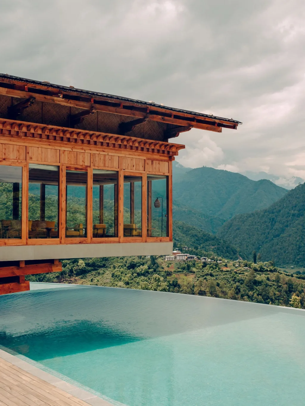 Cantilevered wood-and-glass pavilion over an infinity pool at Six Senses Bhutan hotel