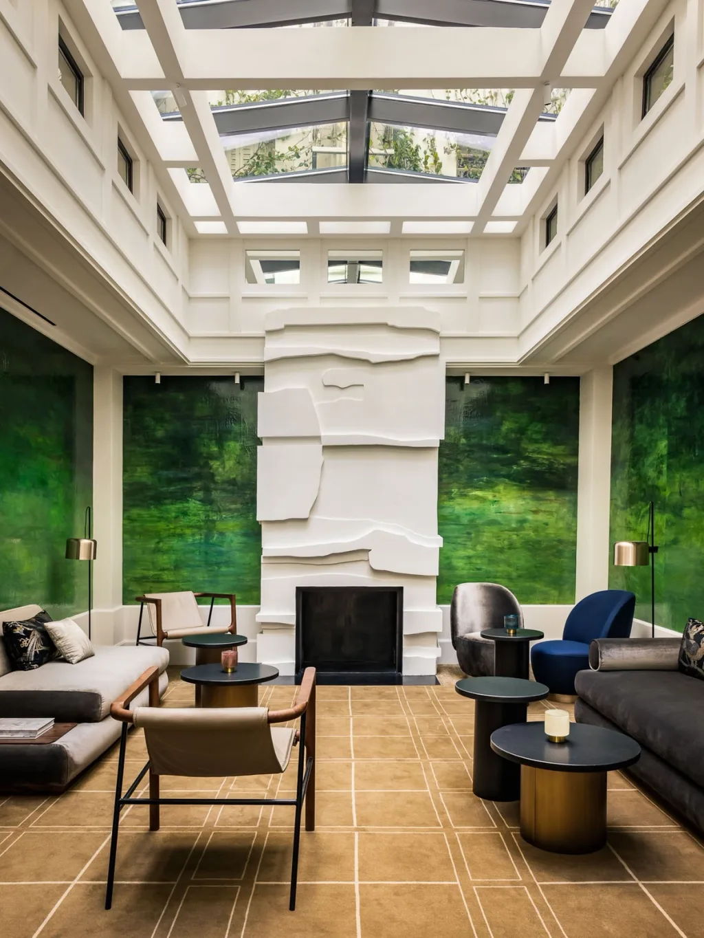 Skylit lounge with a sculpted white fireplace and emerald wall panels at Hotel Pavillon St Germain, Paris