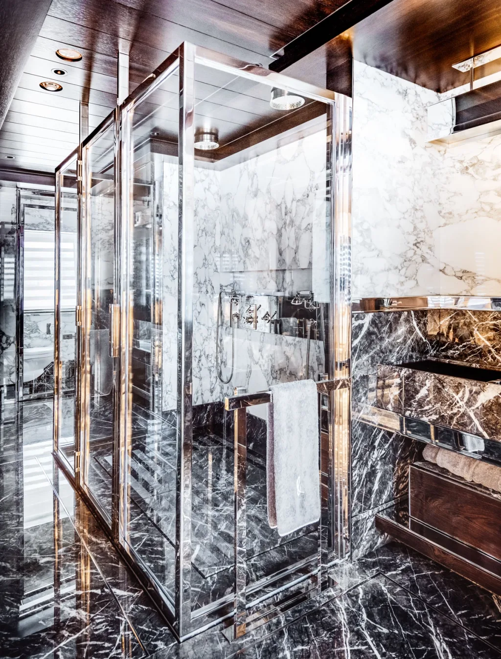 Glass shower enclosure amid strongly veined black and white surfaces aboard Atlante