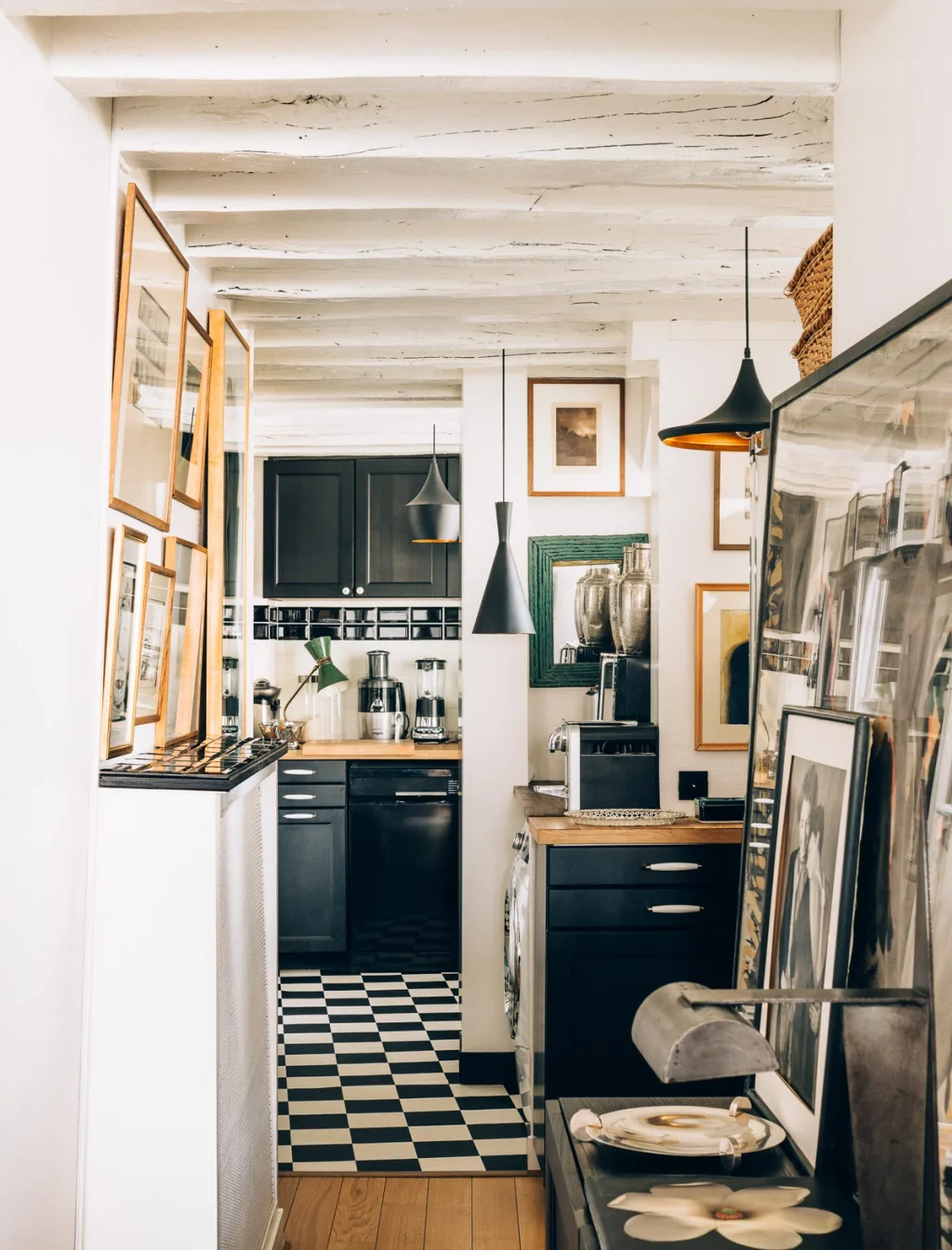 Narrow art-lined passage leading to a black kitchen and chequered floor, Michel Klein, Paris