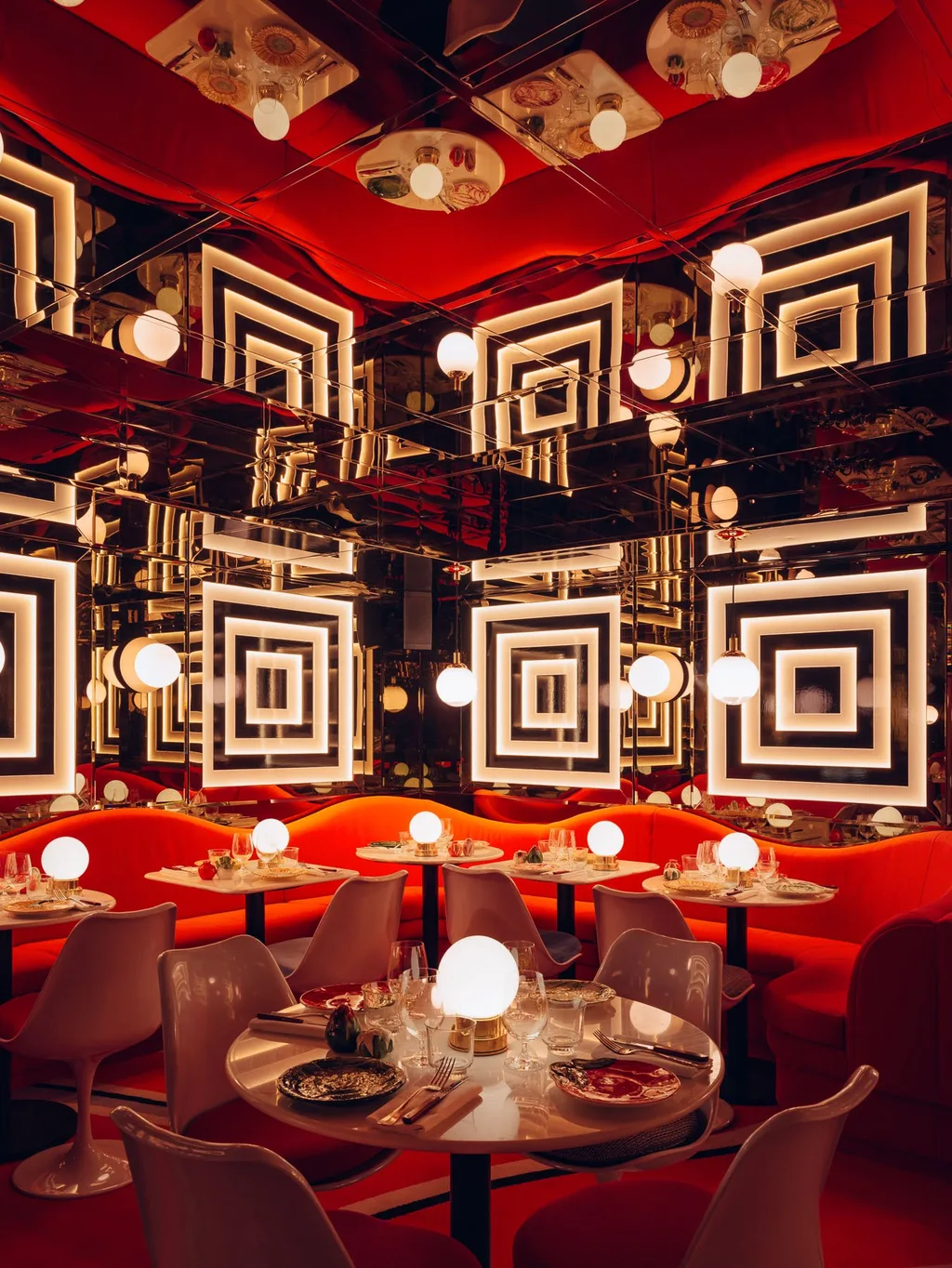 Red banquettes and illuminated square mirrors in a Big Mamma dining room, UK