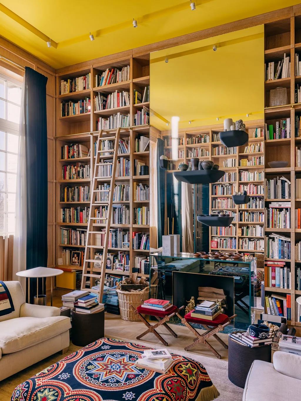 Tall library shelves beneath a yellow ceiling in Laurent Buttazzoni's Paris interior