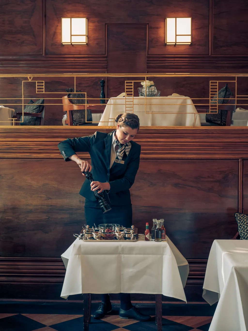 Waiter using a pepper mill over a trolley in a wood-panelled room at Fairmont Hotel, Hamburg
