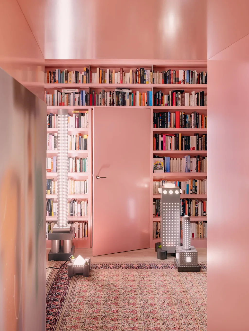 Pink passage opening onto bookshelves and sculptural lamps in a Laurent Buttazzoni interior, Paris