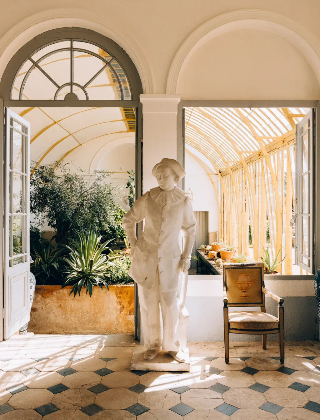 White standing statue beside an open doorway to the conservatory at Chateau de Digoine