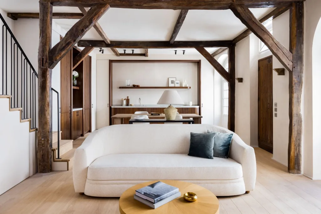 White curved sofa beneath exposed timber beams in Hugues de Blignières' Paris interior