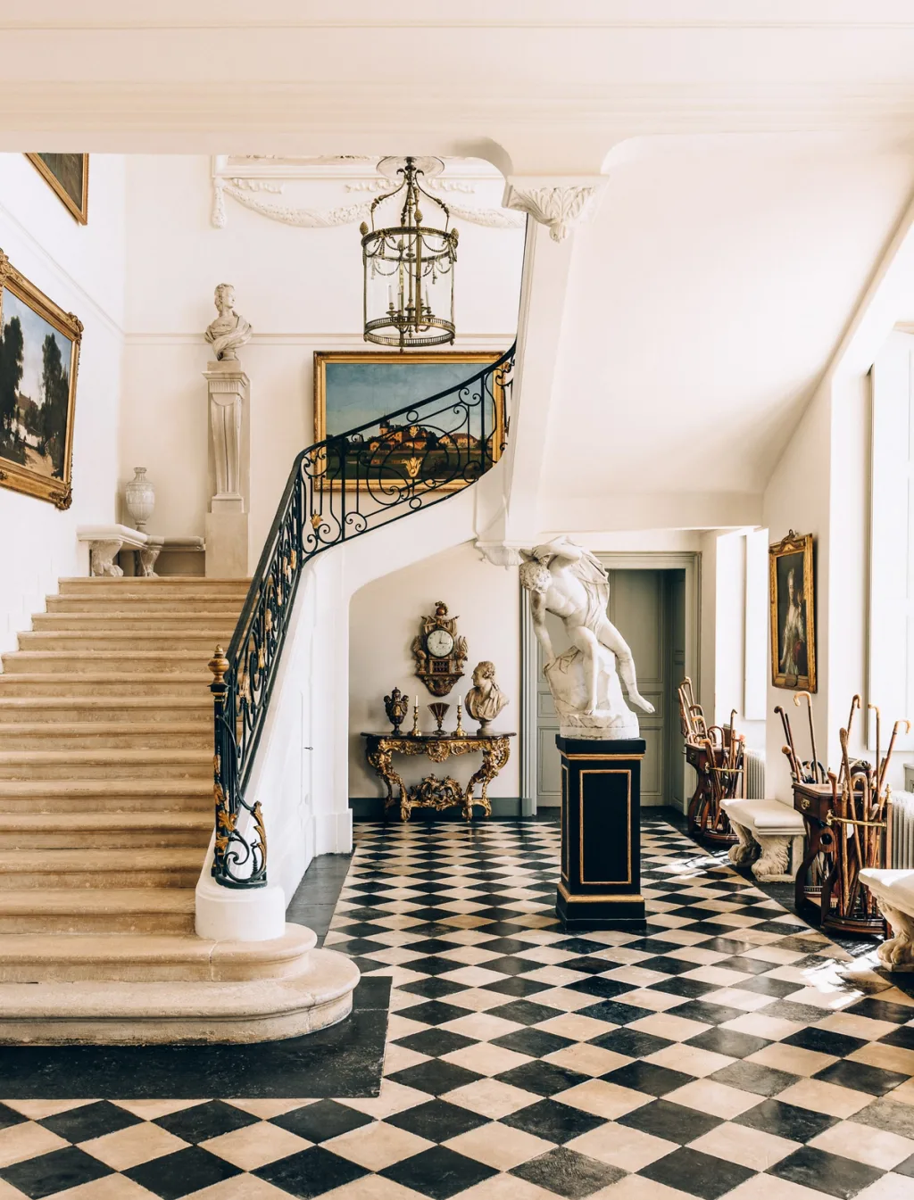 Sweeping staircase above a chequered hall with sculptures at Chateau de Digoine