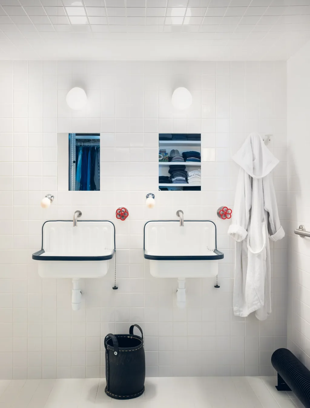 Two wall-mounted basins with red tap wheels in Daniel Rozensztroch's white-tiled Paris bathroom