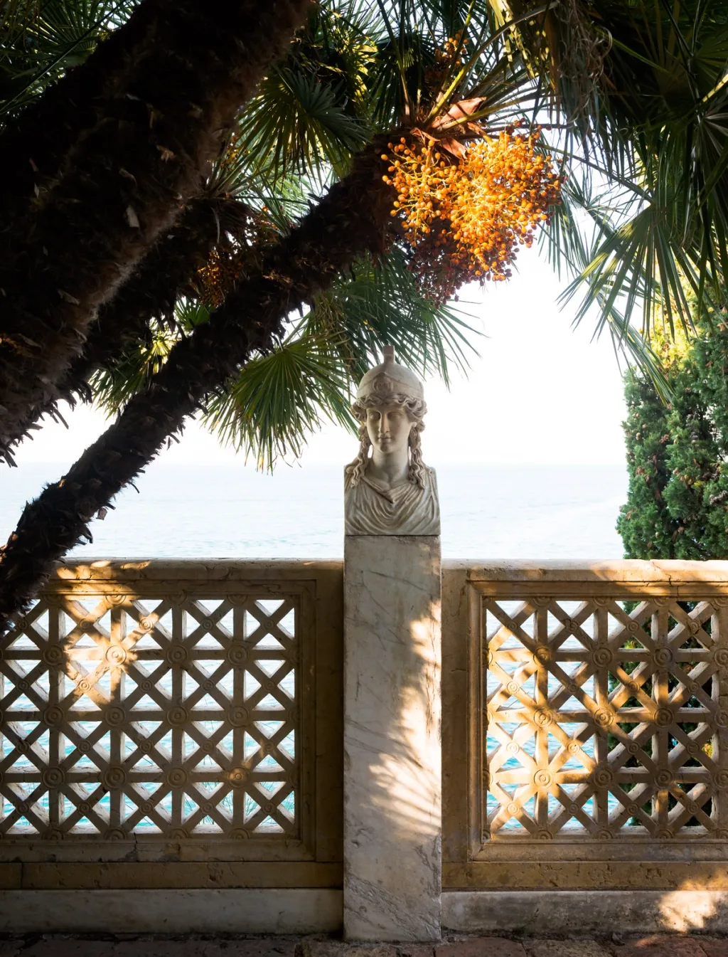 Sculpted bust on a tall pedestal beside a patterned sea-view balustrade at Villa Astor