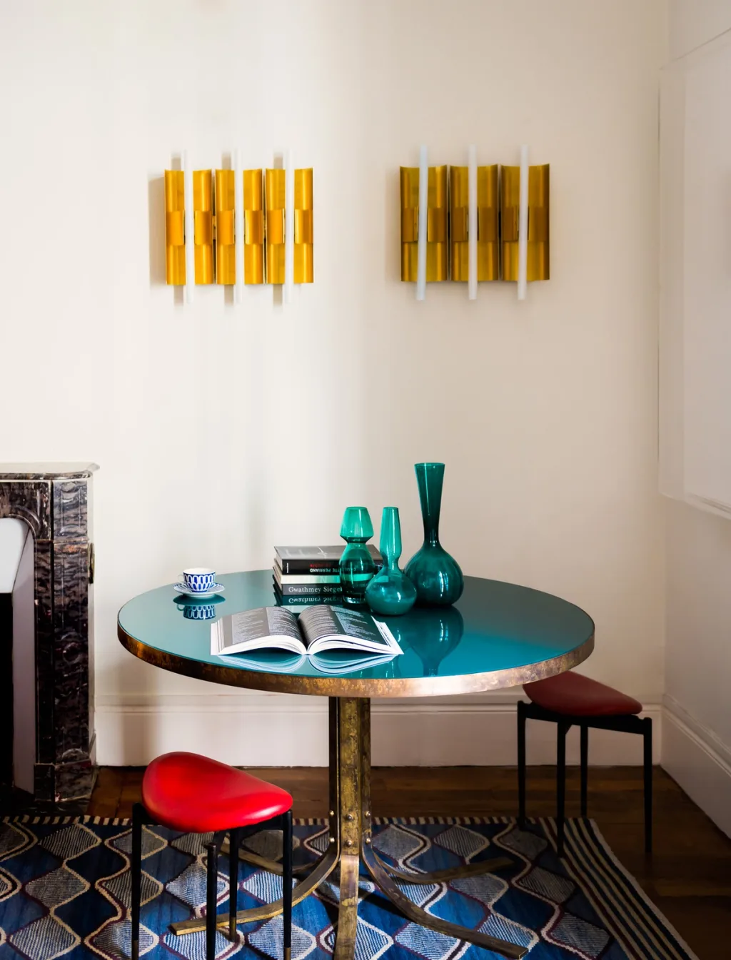 Turquoise round table with green vessels beneath paired gold wall lights, Dimore Studio, Paris