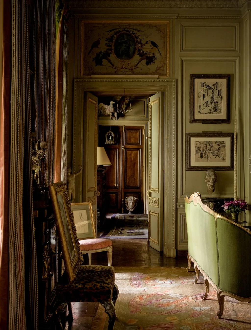 Green-backed sofa and framed art beside an ornate open doorway, Pierre Bergé, Paris