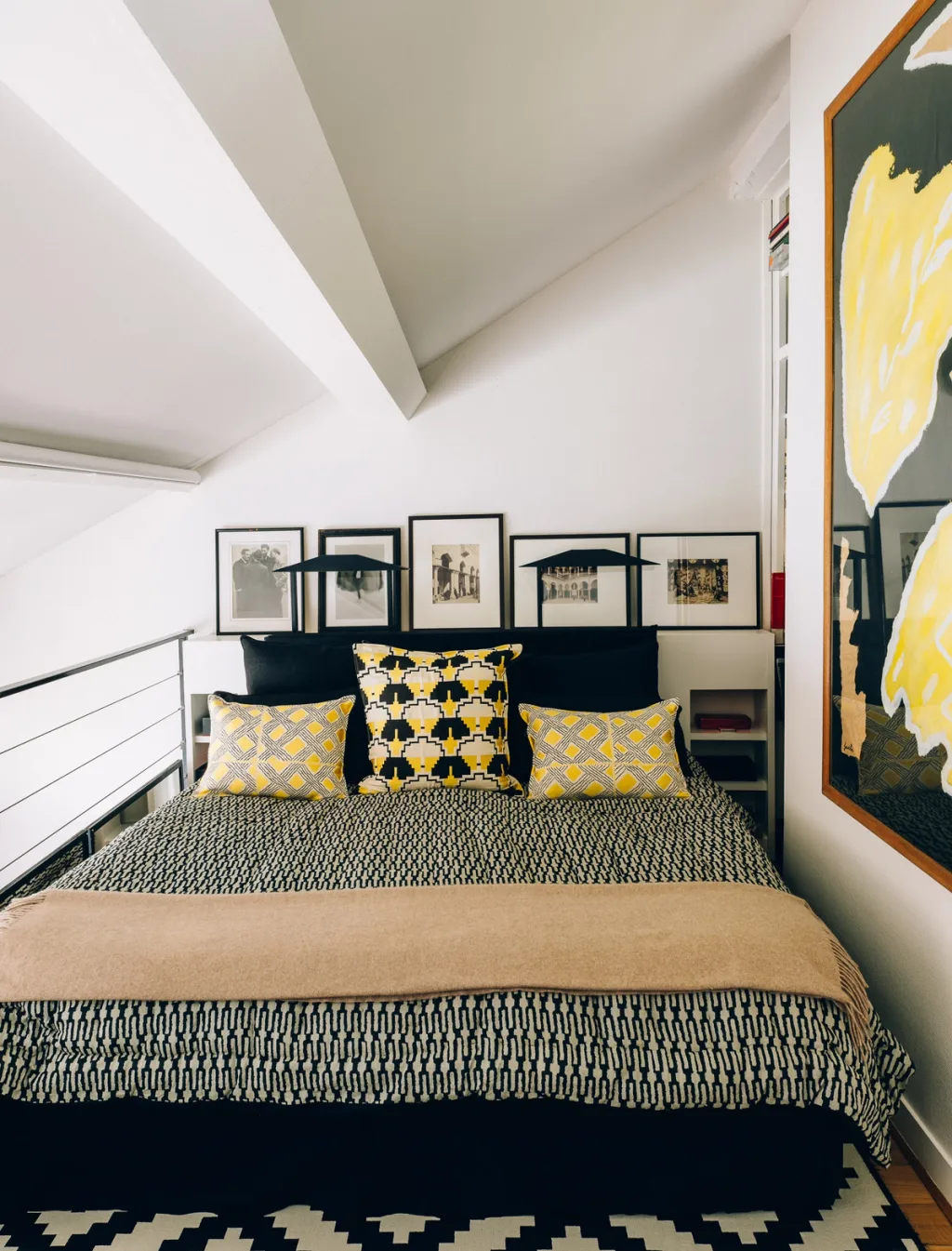 Mezzanine bedroom with patterned yellow cushions beneath a sloping ceiling, Michel Klein, Paris
