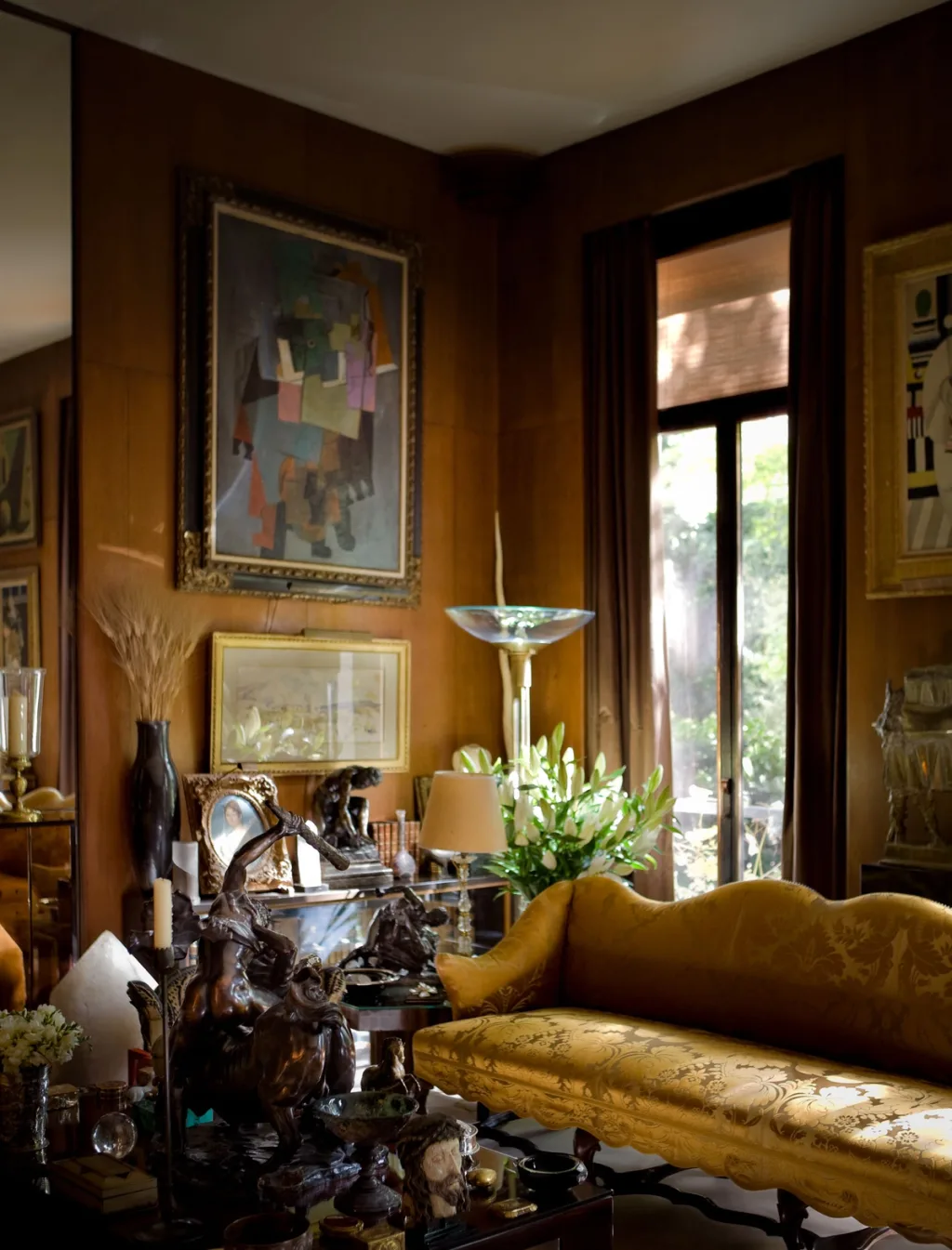 Golden sofa beneath paintings beside a tall window, Yves Saint Laurent, Paris