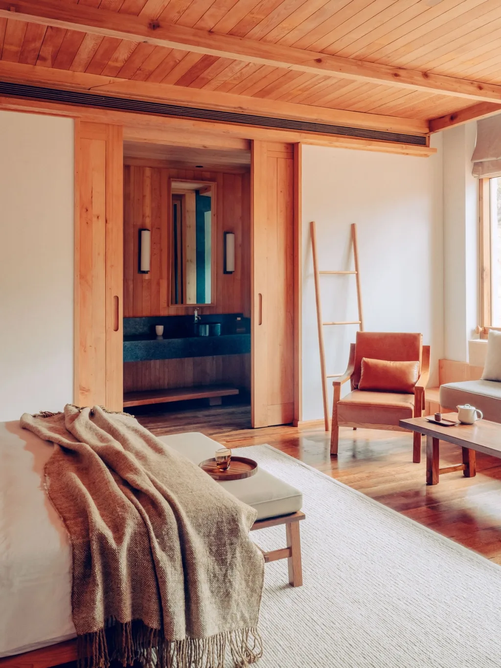 Suite with a wood-paneled bathroom, ladder, and leather armchair at Six Senses Bhutan hotel