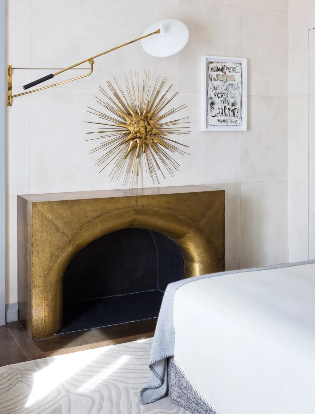 Gold-toned fireplace and sunburst ornament beside a white bed, Jean Louis Deniot, Paris