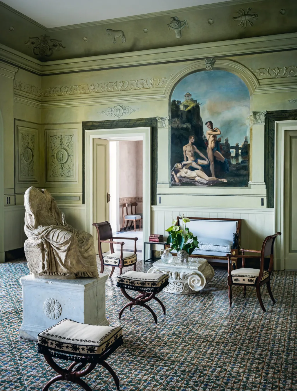 Pale green salon with painted walls, a seated sculpture and patterned floor at Villa Astor