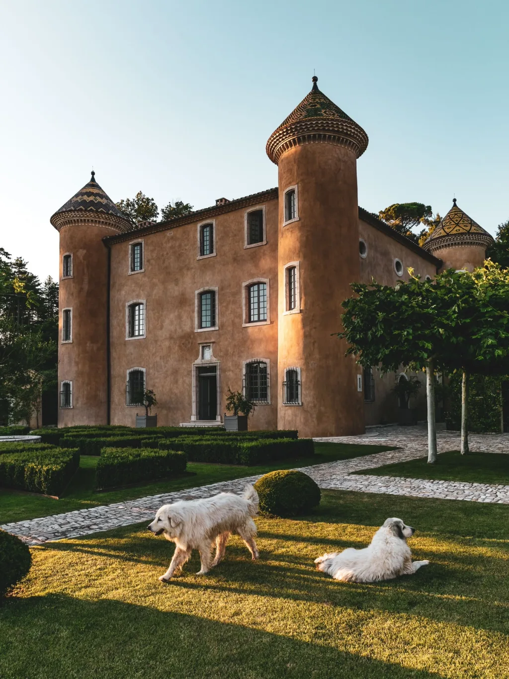 Two white dogs on the lawn before the turreted facade of Fabrègues, Pierre Yovanovitch