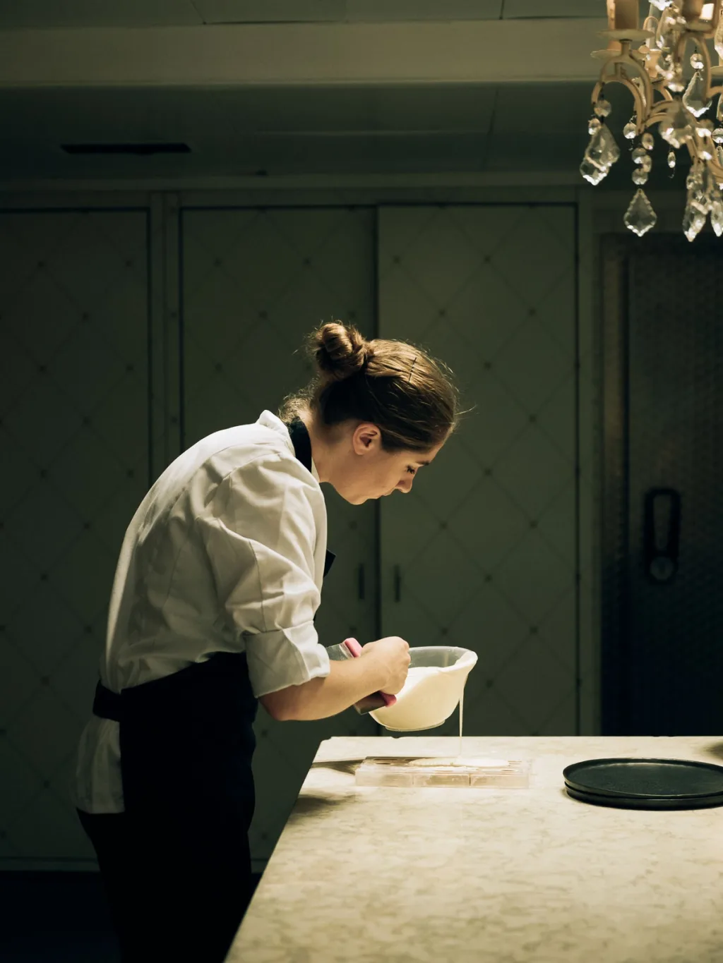 Chef working with a mixing bowl at a pale kitchen counter at Fairmont Hotel, Hamburg