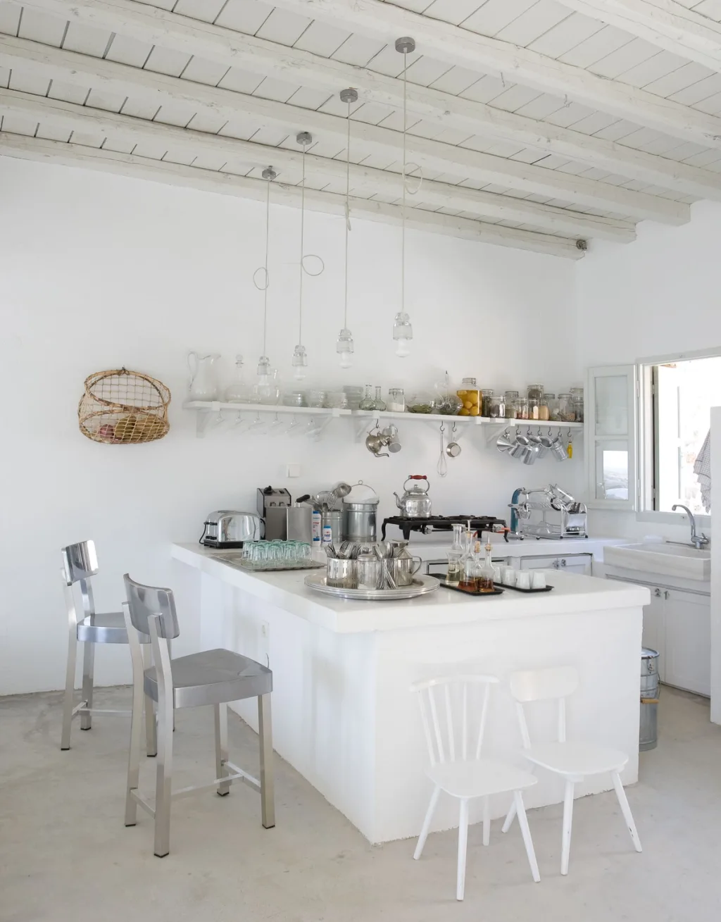 White kitchen island beneath exposed rafters and dangling lights, Paola Navone, Serifos
