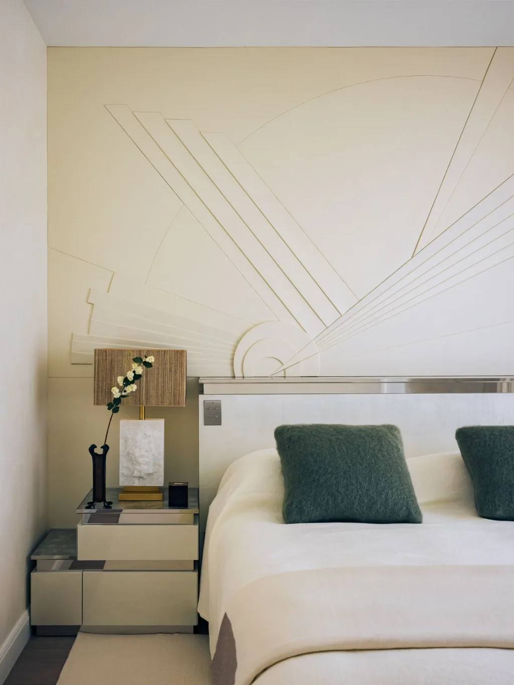 White bed beneath a geometric wall relief in Stéphanie Coutas' Paris interior