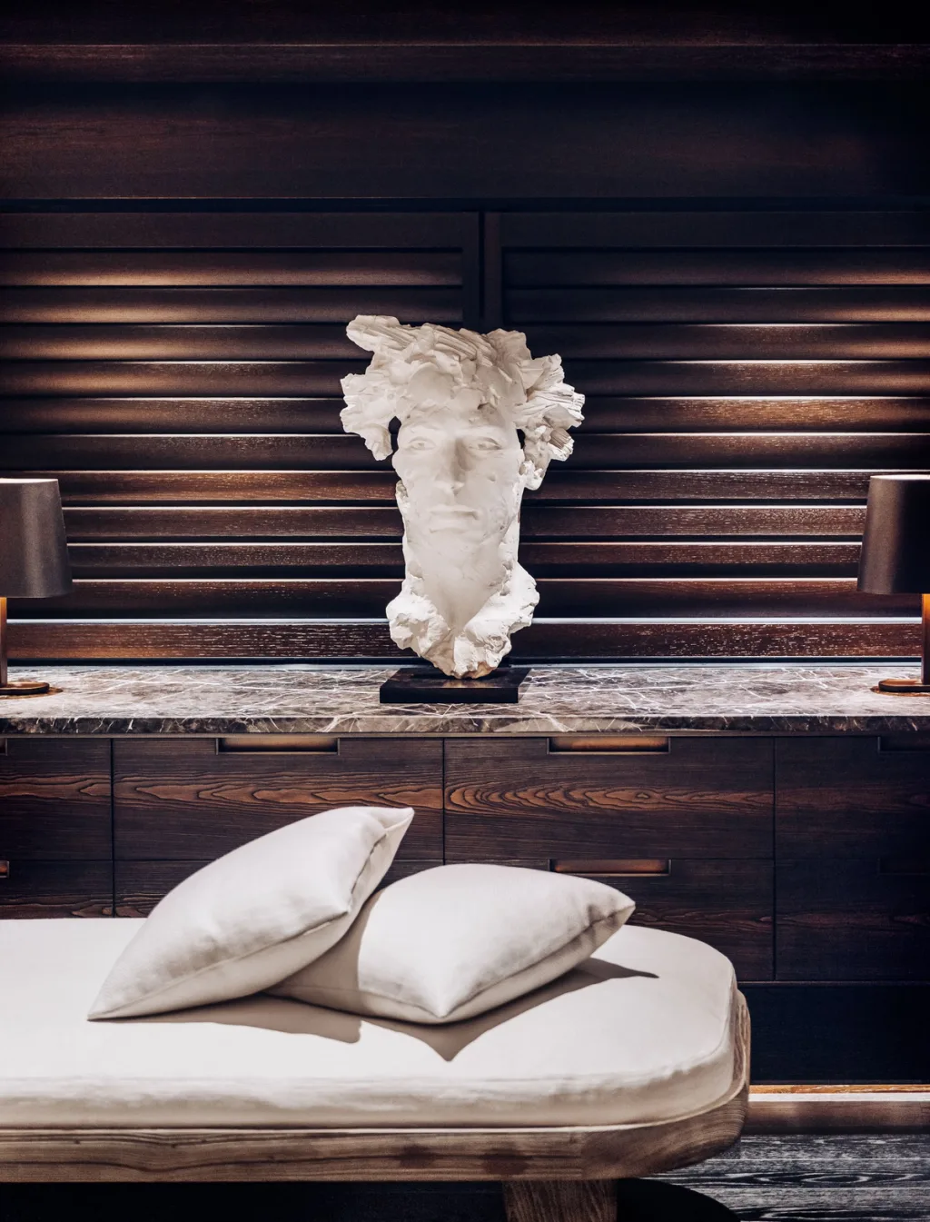White sculpted head above a cushioned chaise against dark slatted walls aboard Atlante