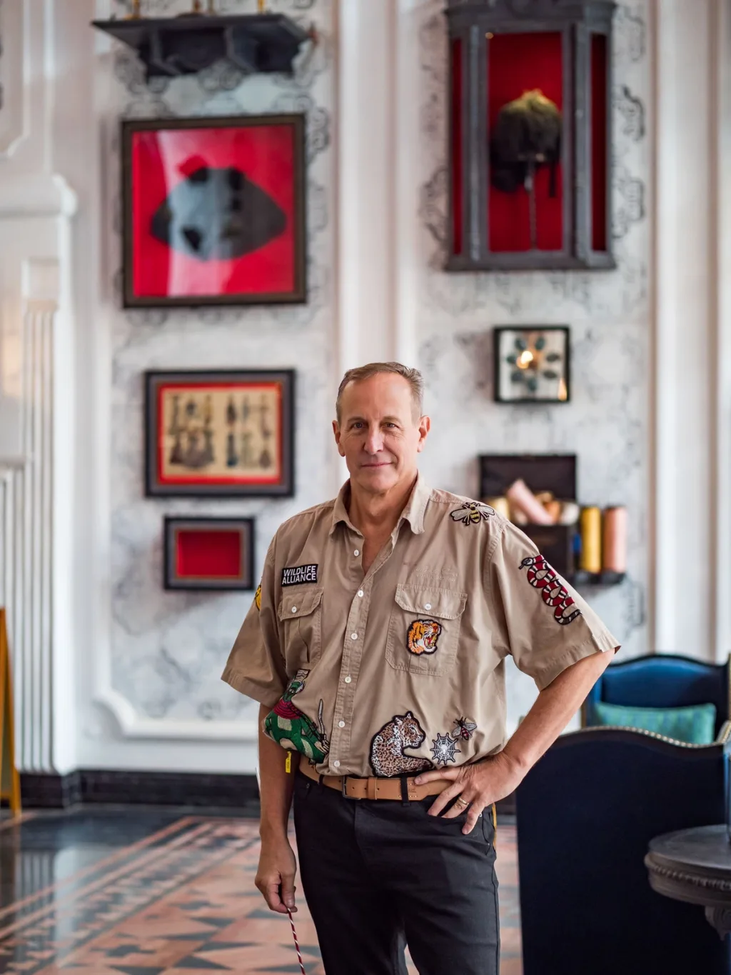 Man in a wildlife-patch shirt stands before red display cases, Hotel de la Coupole MGallery, Sapa, Vietnam