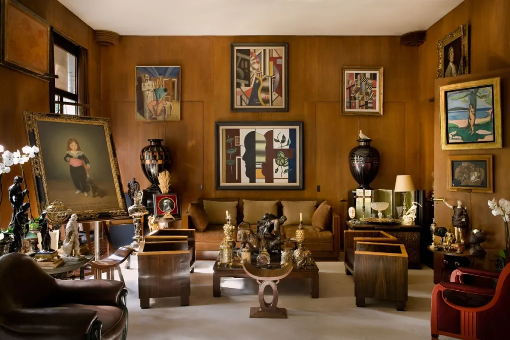 Art-filled living room with golden walls, angular chairs and low tables, Yves Saint Laurent, Paris