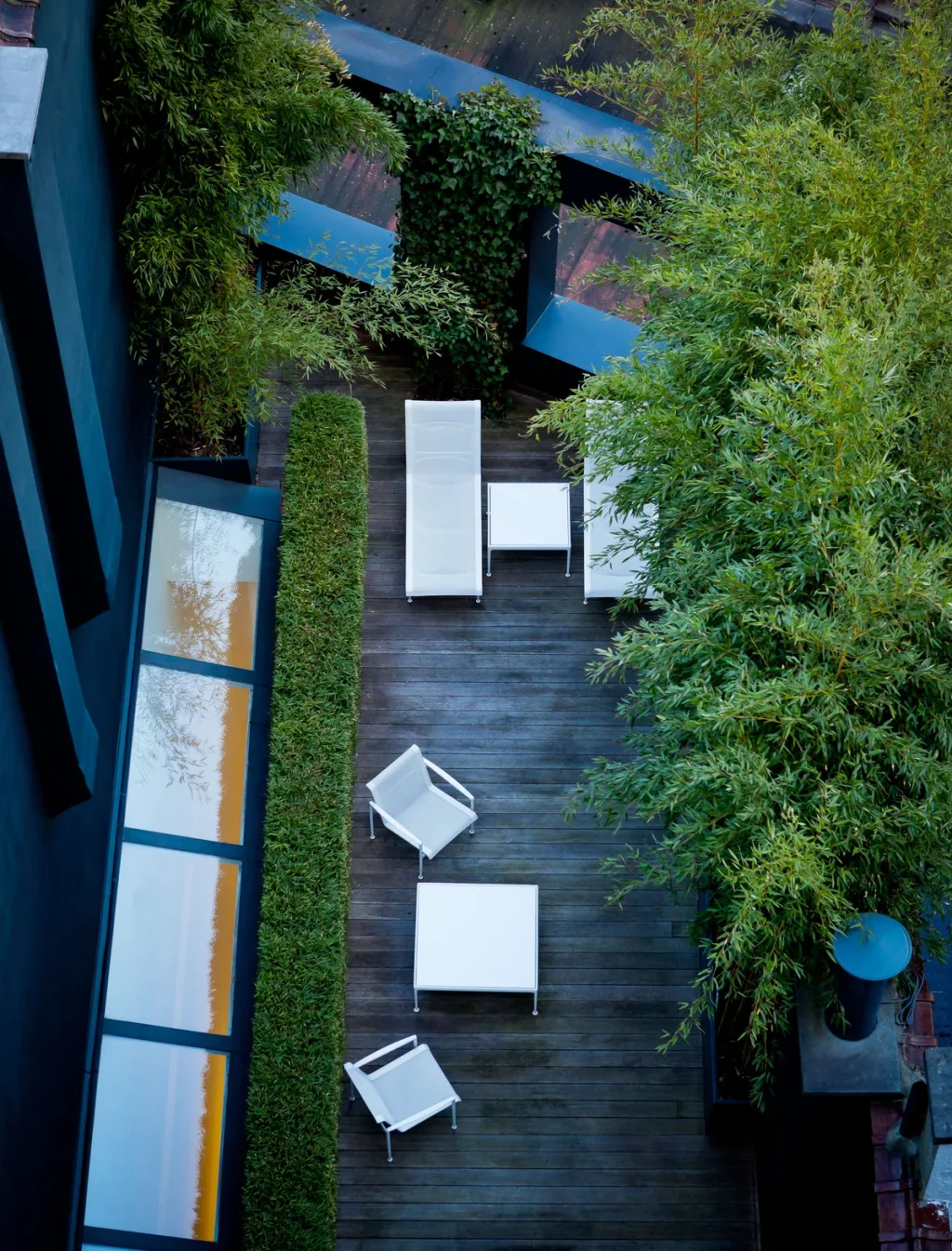 Overhead view of white outdoor furniture on a leafy enclosed terrace in the James Van Damme series