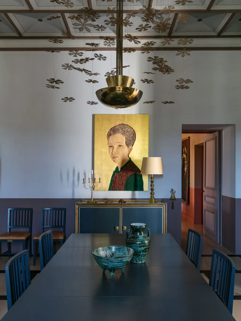 Dark dining table beneath a floral chandelier and portrait at Fabrègues, Pierre Yovanovitch