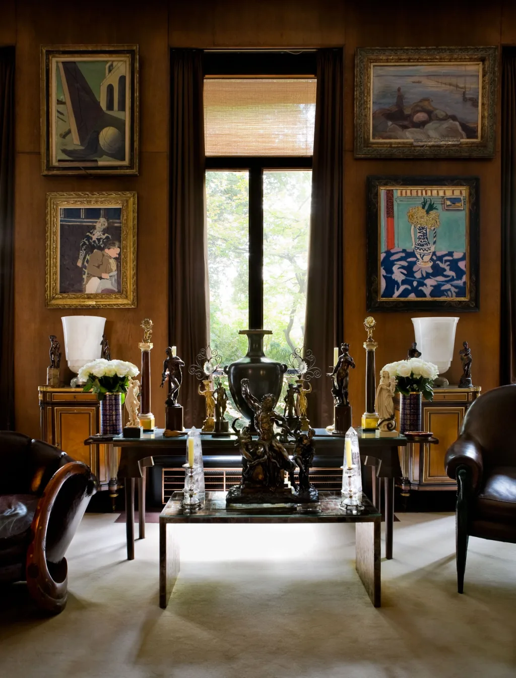 Paintings surrounding a tall window above tables of decorative objects, Yves Saint Laurent, Paris
