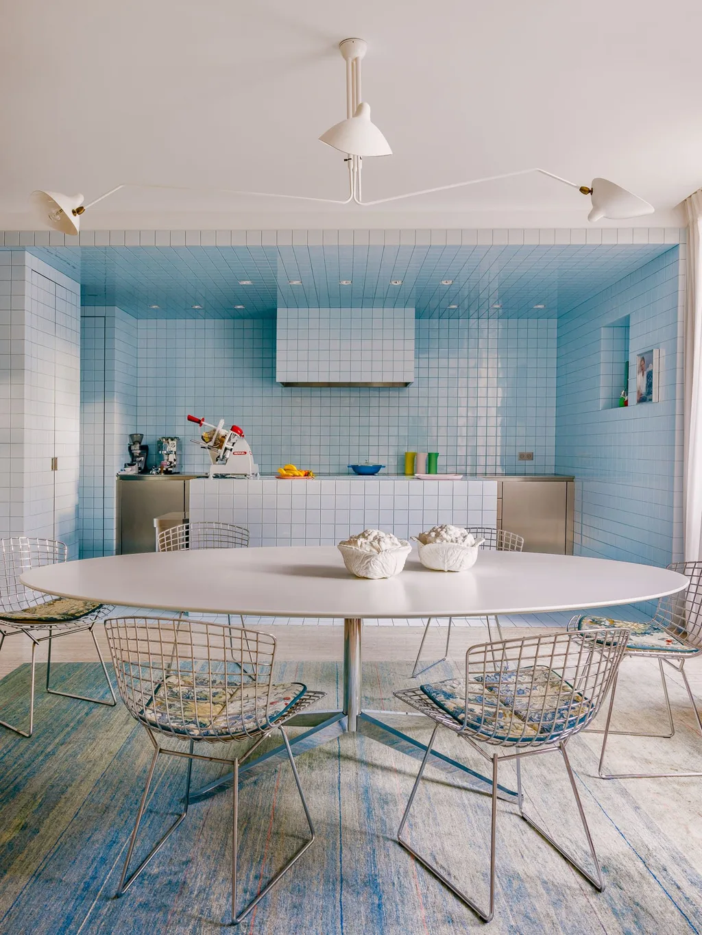Pale blue tiled kitchen with an oval table in Laurent Buttazzoni's Paris interior
