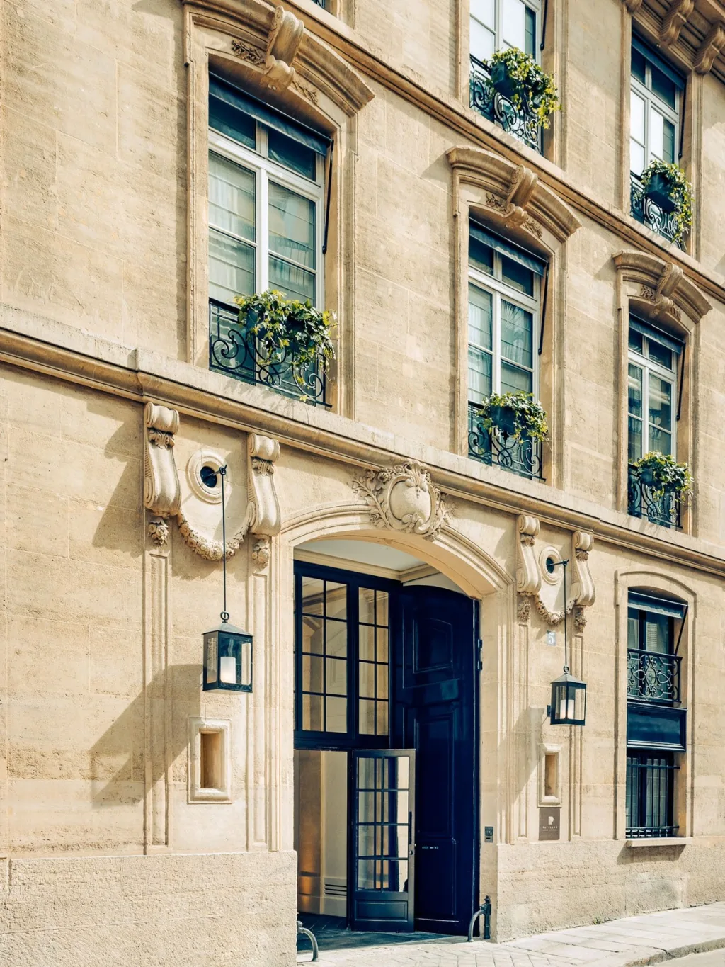 Carved stone facade with ivy-filled window boxes at Hotel Pavillon St Germain, Paris