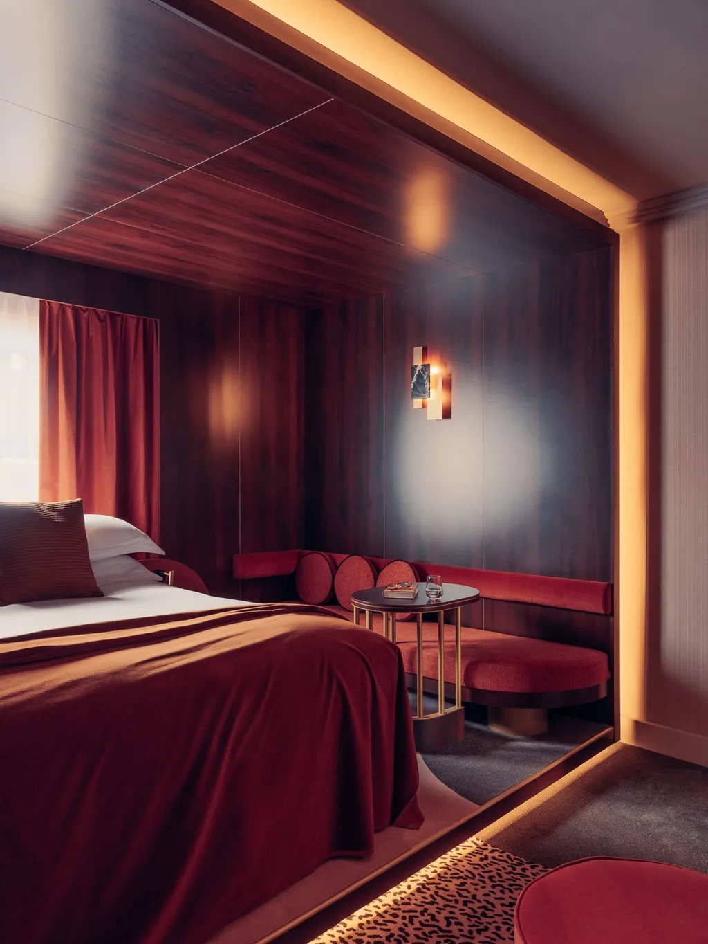 Dark wood bedroom alcove with red velvet bed and curved banquette, Nest MGallery Hotel, Paris