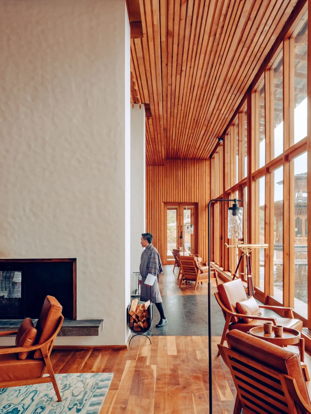 Timber-lined lounge with a telescope and leather chairs overlooking a lake at Six Senses Bhutan hotel